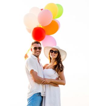 love, wedding, summer, dating and people concept - smiling couple wearing sunglasses with balloons hugging outdoors