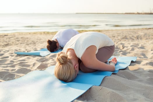 fitness, sport, people and lifestyle concept - close up of couple making yoga exercises on mats outdoors