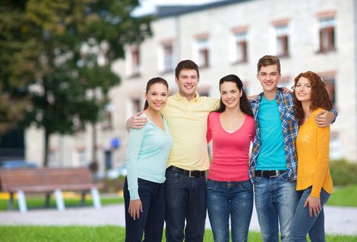 friendship, education, summer vacation and people concept - group of smiling teenagers standing and hugging over campus background