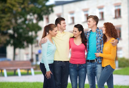 friendship, education, summer vacation and people concept - group of smiling teenagers standing and hugging over campus background