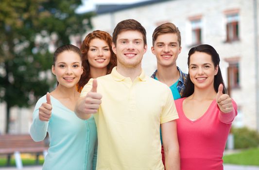 friendship, education, summer vacation and people concept - group of smiling teenagers showing thumbs up over campus background