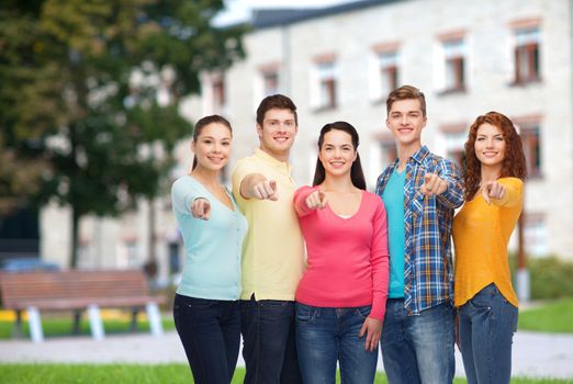 friendship, education, summer vacation and people concept - group of smiling teenagers pointing finger on you over campus background