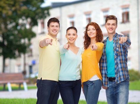 friendship, education, summer vacation and people concept - group of smiling teenagers pointing finger on you over campus background