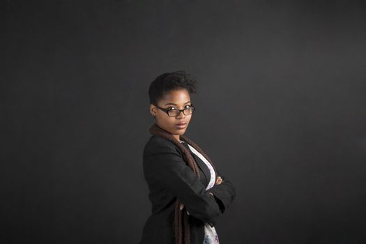 South African or African American woman teacher or student with arms folded on chalk black board background