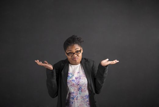 South African or African American black woman teacher or student posing with an "I don't know" gesture on a chalk blackboard background inside