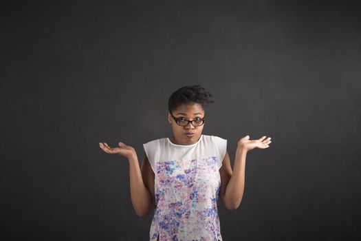 South African or African American black woman teacher or student posing with an "I don't know" gesture on a chalk blackboard background inside