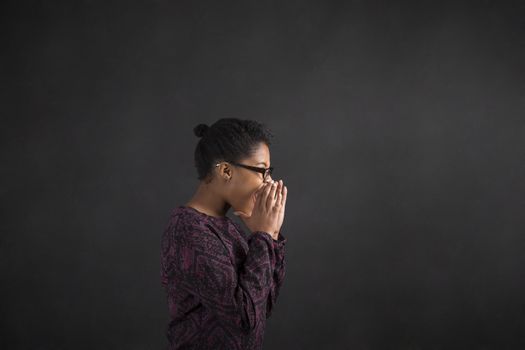 South African or African American black woman teacher or student shouting or screaming standing against a chalk blackboard background inside