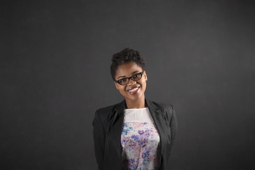 South African or African American black woman teacher or student with her arms behind her back on chalk black board background inside