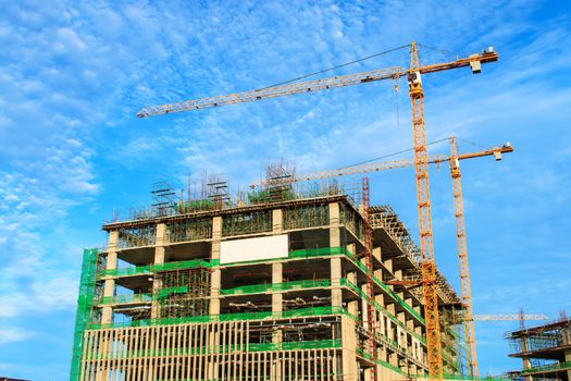 High rise building under construction. The site with cranes against blue sky