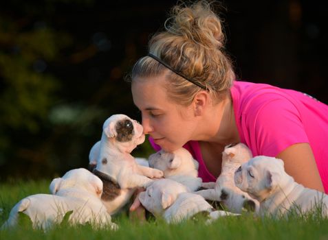 woman playing in the grass with litter of puppies