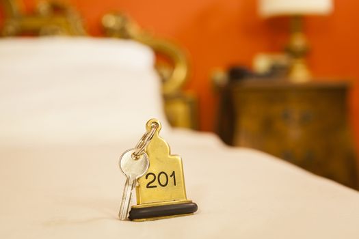 Hotel Room Key lying on Bed with keyring golden