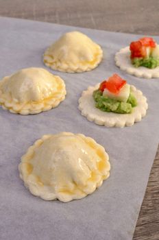 Stuffed avocado with cheese and tomato on a slice of puff pastry