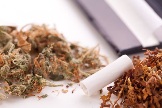 Close up Dried Cannabis Leaves on a Resealable Cellophane Wrapper and a Rolling Paper with Filter on Top of the Table