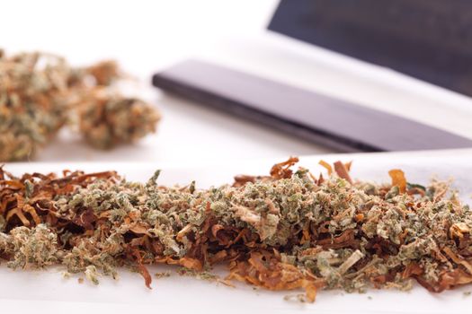 Close up Dried Cannabis Leaves on a Resealable Cellophane Wrapper and a Rolling Paper with Filter on Top of the Table