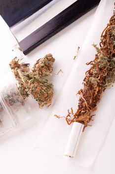 Close up Dried Cannabis Leaves on a Resealable Cellophane Wrapper and a Rolling Paper with Filter on Top of the Table