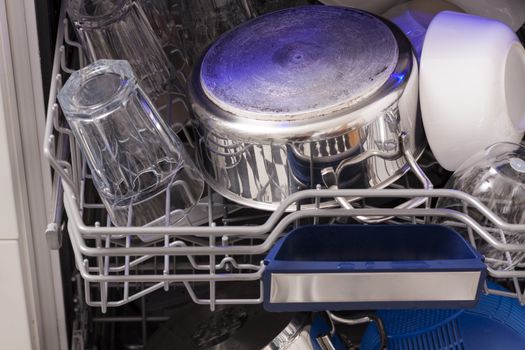 Dishwasher loades in a kitchen with clean dishes and blue light