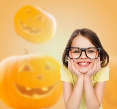 education, holidays, childhood, vision and people concept - smiling little girl in glasses over halloween pumpkins background