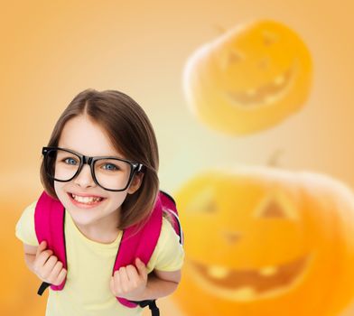 education, holidays, childhood, vision and people concept - smiling little girl in glasses over halloween pumpkins background