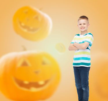 holidays, childhood, happiness and people concept - smiling little boy over halloween pumpkins background