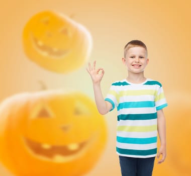 holidays, childhood, happiness, gesture and people concept - smiling little boy showing ok sign over halloween pumpkins background