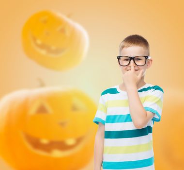 education, holidays, childhood, vision and people concept - smiling little boy in glasses over halloween pumpkins background