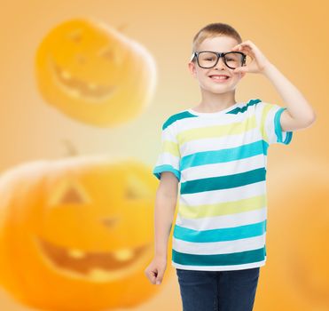 education, holidays, childhood, vision and people concept - smiling little boy in glasses over halloween pumpkins background