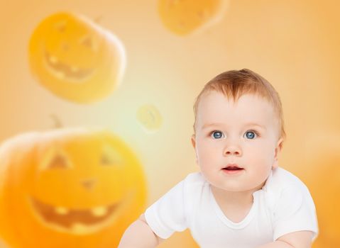 holidays, childhood, happiness and people concept - smiling baby over pumpkins background