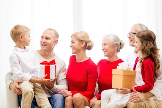 family, holidays, generation, christmas and people concept - smiling family with gift boxes sitting on couch at home