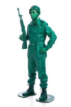 Man on a green toy soldier costume standing with riffle isolated on white background.