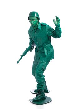 Man on a green toy soldier costume with riffle waving to be followed  isolated on white background.