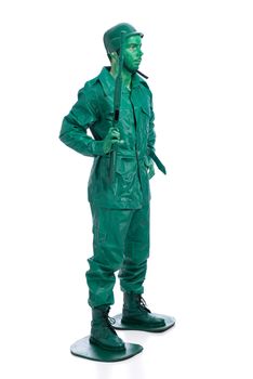 Man on a green toy soldier costume standing with riffle isolated on white background.