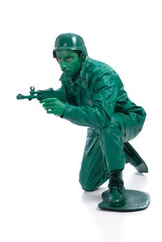 Man on a green toy soldier costume standing on one knee with riffle isolated on white background.