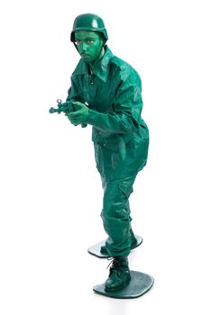 Man on a green toy soldier costume walking with riffle isolated on white background.