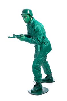 Man on a green toy soldier costume walking with riffle isolated on white background.