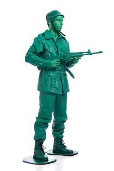 Man on a green toy soldier costume standing with riffle isolated on white background.