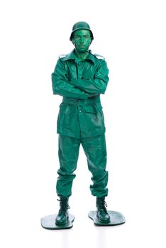 Man on a green toy soldier costume with arms crossed isolated on white background.