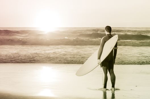 Surfer watching the waves at sunset in Portugal.