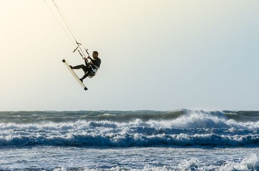 Kitesurfer jumping on a beautiful background of spray during the sunset.