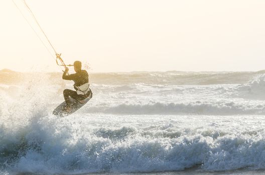 Kitesurfer jumping on a beautiful background of spray during the sunset.