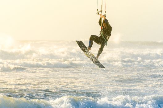 Kitesurfer jumping on a beautiful background of spray during the sunset.