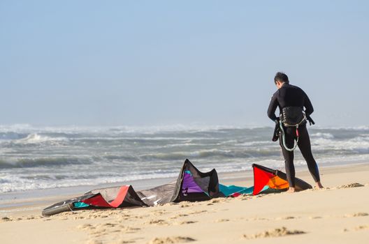 Kitesurfer prepating his equipment on a beautiful sunset at the beach.