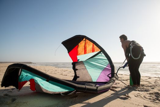 Kitesurfer prepating his equipment on a beautiful sunset at the beach.