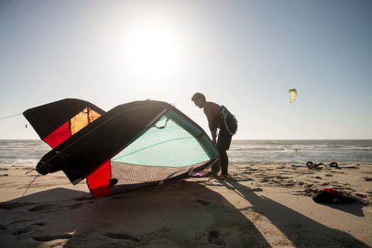 Kitesurfer prepating his equipment on a beautiful sunset at the beach.