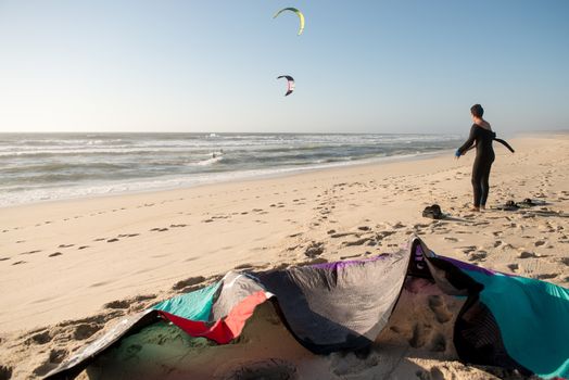 Kitesurfer prepating his equipment on a beautiful sunset at the beach.