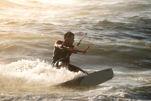 Kitesurfer in action on a beautiful background of spray during the sunset.