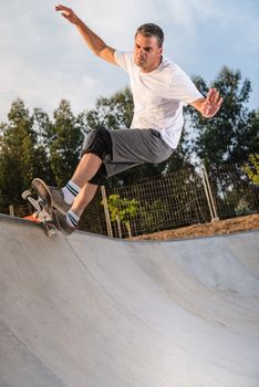 Skateboarder in a concrete pool at skatepark on a beatiful sunset.