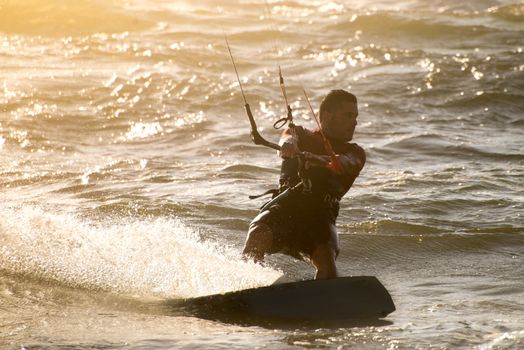 Kitesurfer in action on a beautiful background of spray during the sunset.