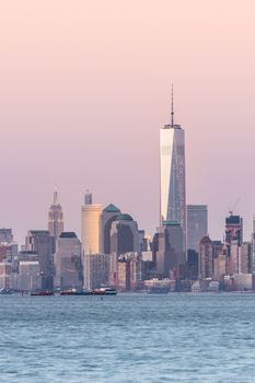 New York City Manhattan downtown skyline at dusk with skyscrapers illuminated over Hudson River panorama. Vertical composition, copy space.