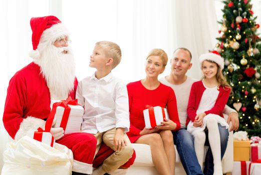 family, holidays, generation, christmas and people concept - smiling family with santa claus and gift boxes at home