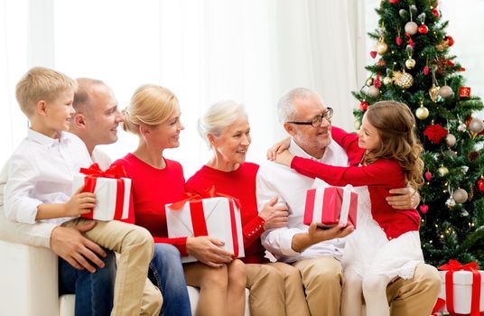 family, holidays, generation, christmas and people concept - smiling family with gift boxes sitting on couch at home